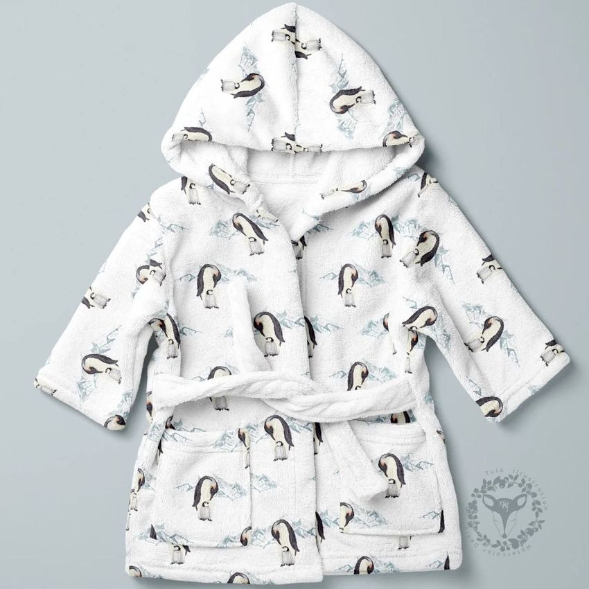 Baby bath dressing gown mockup featuring a white hooded robe with penguin and iceberg patterns, displayed on a light gray background.