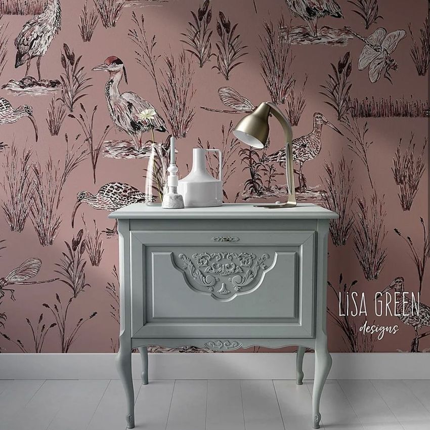 Interior scene mockup showing a vintage light blue cabinet against a pink wallpaper with illustrated wetland birds and grasses.