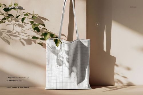 PSD mockup showing a rectangular tote bag with grid design, plant shadows falling across a neutral background.