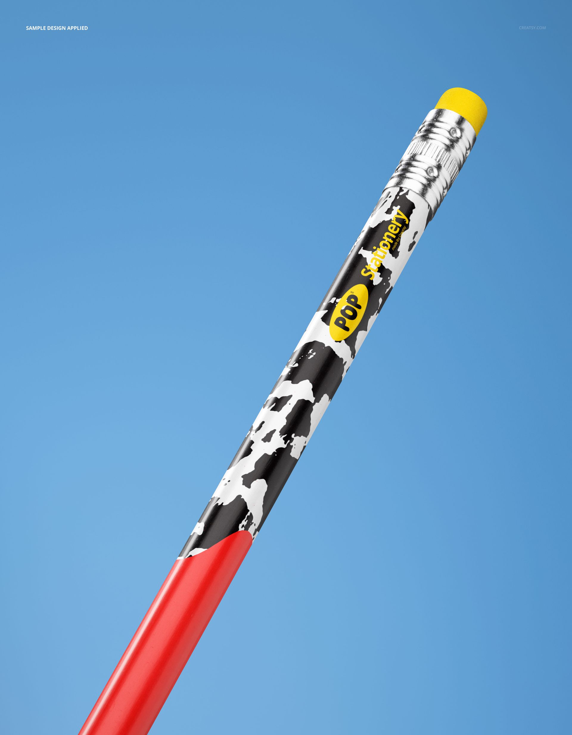 Close-up view of a round pencil mockup with a red lower half, black and white pattern, and yellow eraser against a blue background.