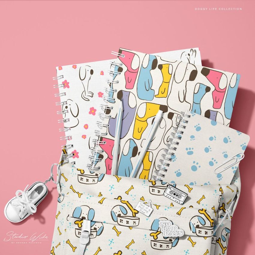 School backpack mockup with spiral notebooks featuring playful dog illustrations and paw print patterns on a pink background.