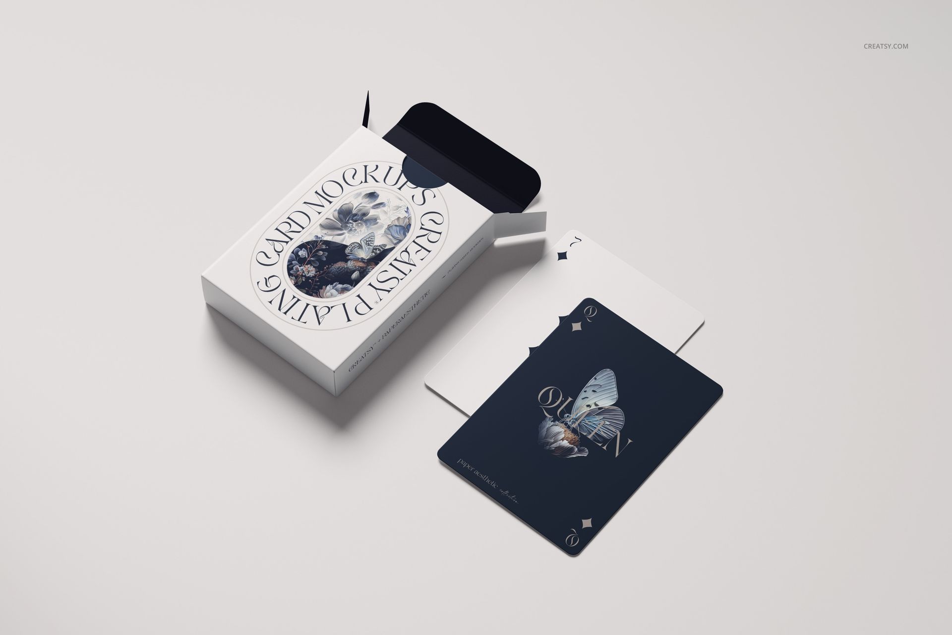 Top view of a playing cards mockup featuring a white box and three cards, including a dark card with butterfly artwork.