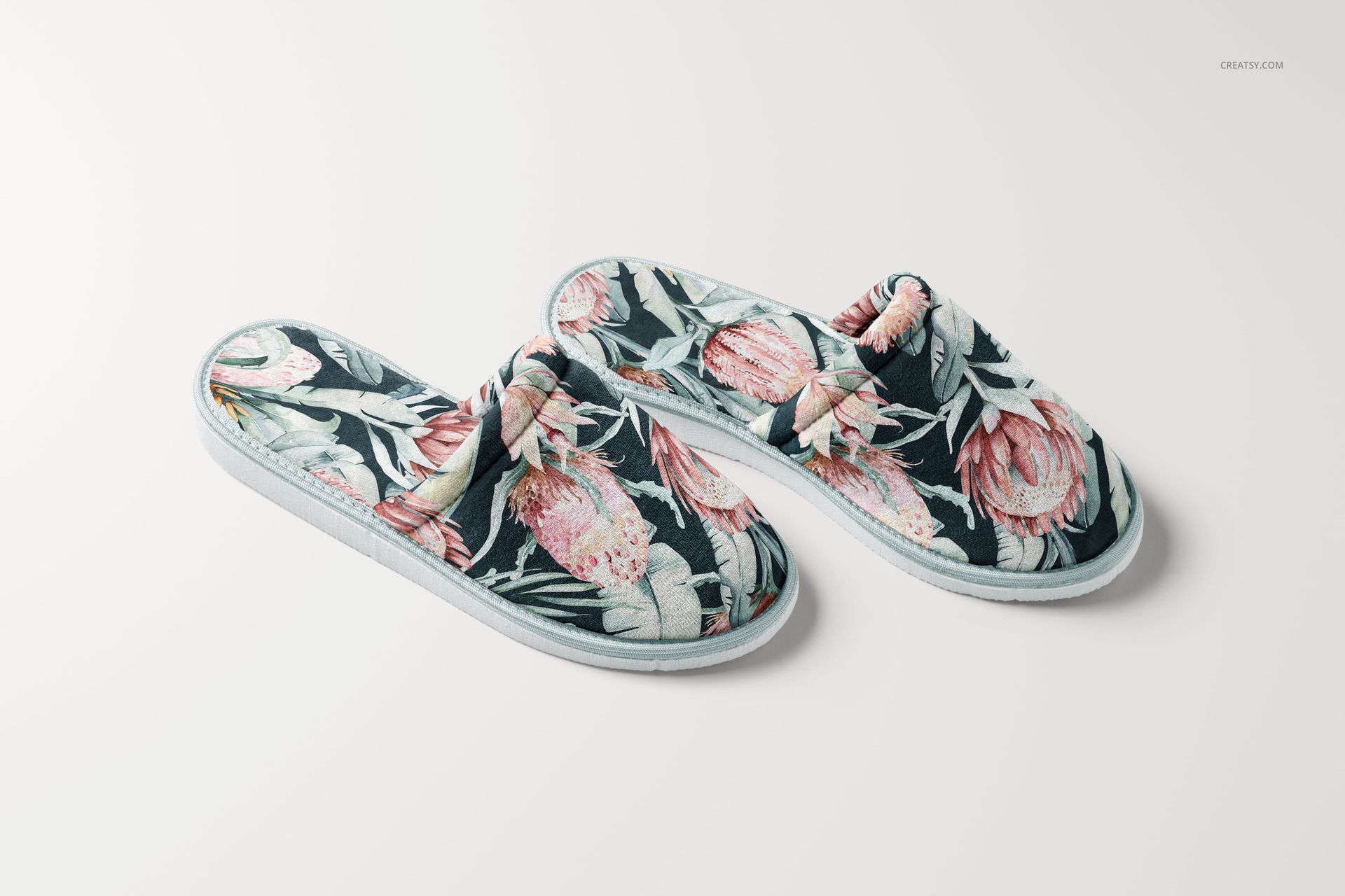 PSD mockup of two home slippers with botanical design, arranged on a clean white surface, semi-top perspective.
