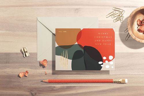 Mockup set showing a card with modern abstract artwork, beige envelope, pencil, and paperclips on a wooden table.
