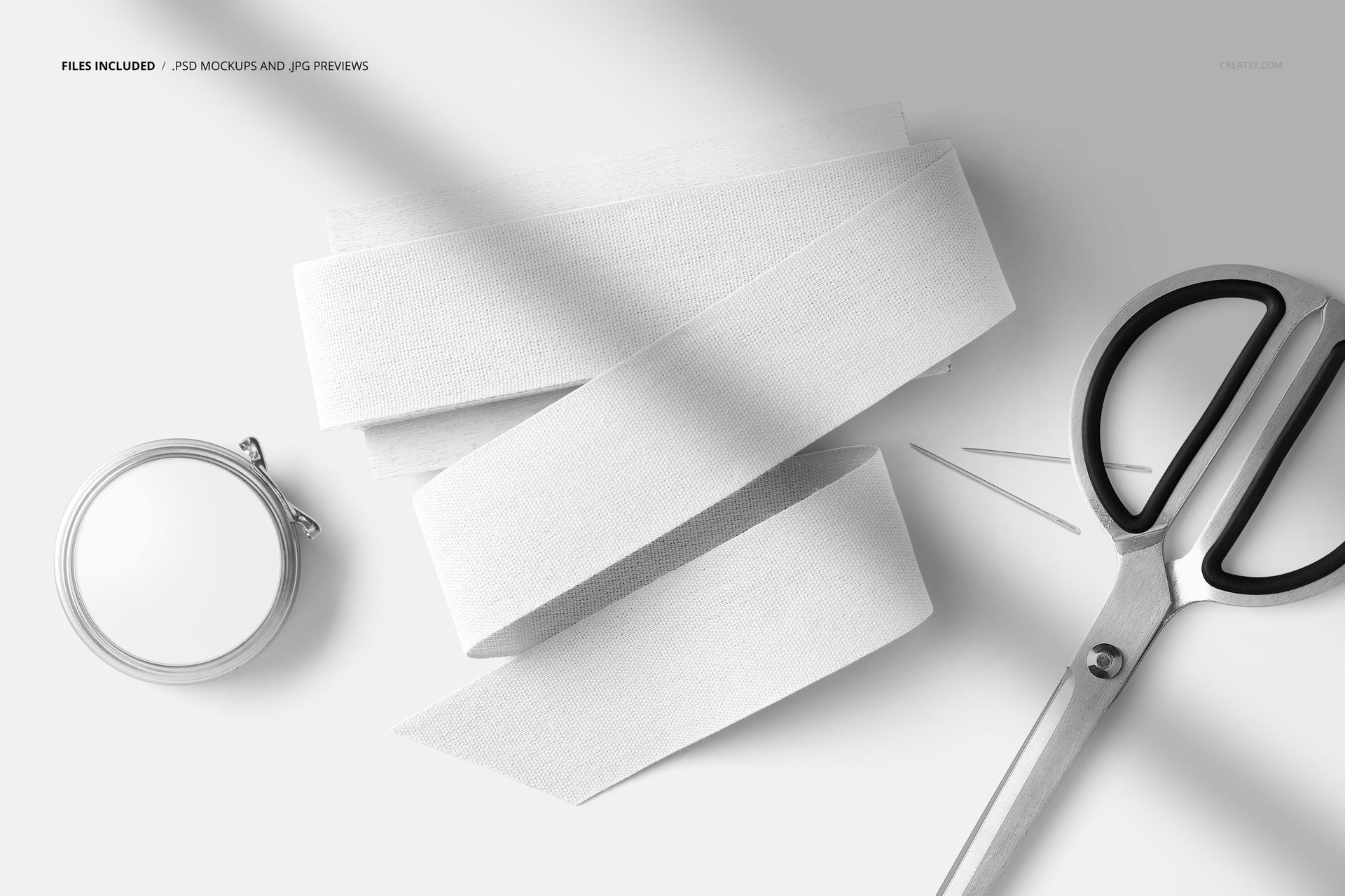 Flat lay of a sewing kit mockup featuring folded white cotton ribbon, scissors, needle, and a small tin box.