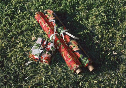 PSD mockup featuring patterned fabric rolls and stacks arranged outdoors on lush green grass, viewed from above.