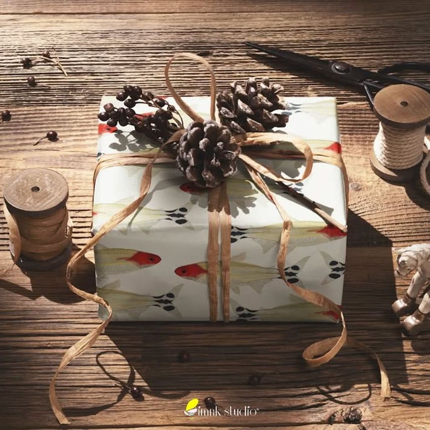 Vintage Christmas gift mockup featuring a wrapped present with pinecones and twine on a rustic wooden table.