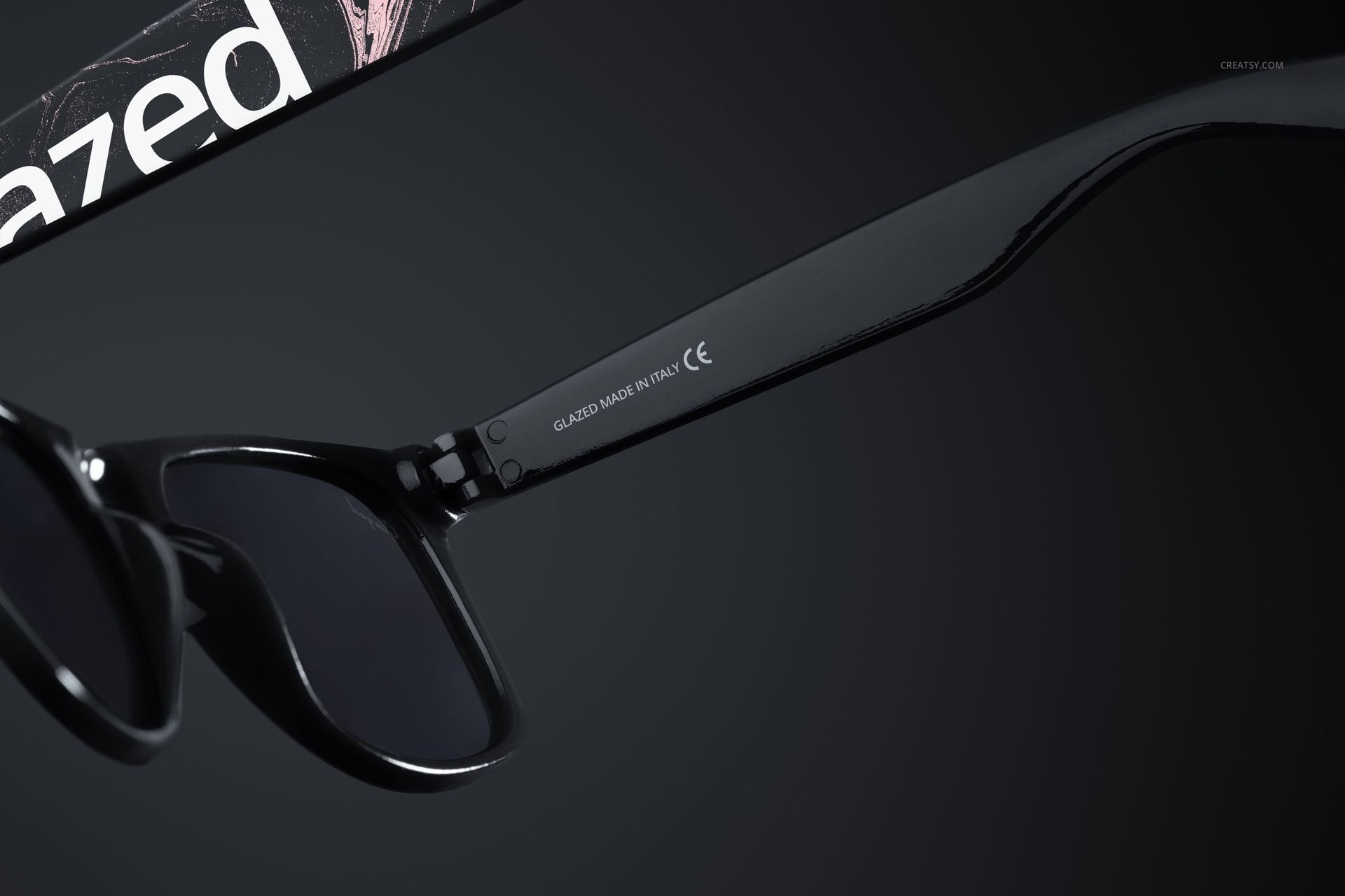 PSD mockup showing black sunglasses with sleek arms and tinted lenses, photographed from a side angle.