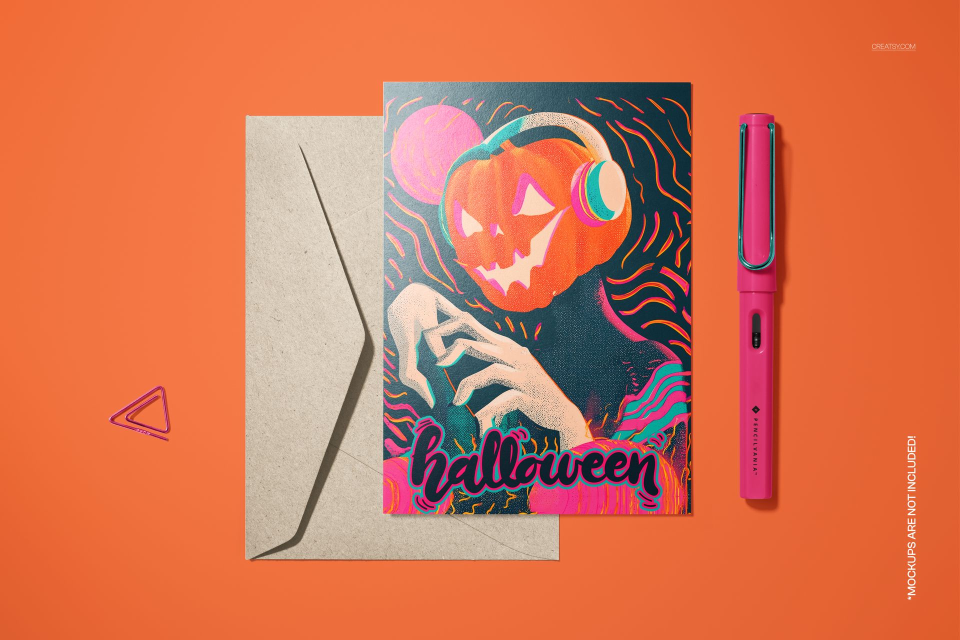 PSD mockup of a folded Halloween card displaying a colorful pumpkin DJ artwork, envelope, and pink pen arranged nearby.