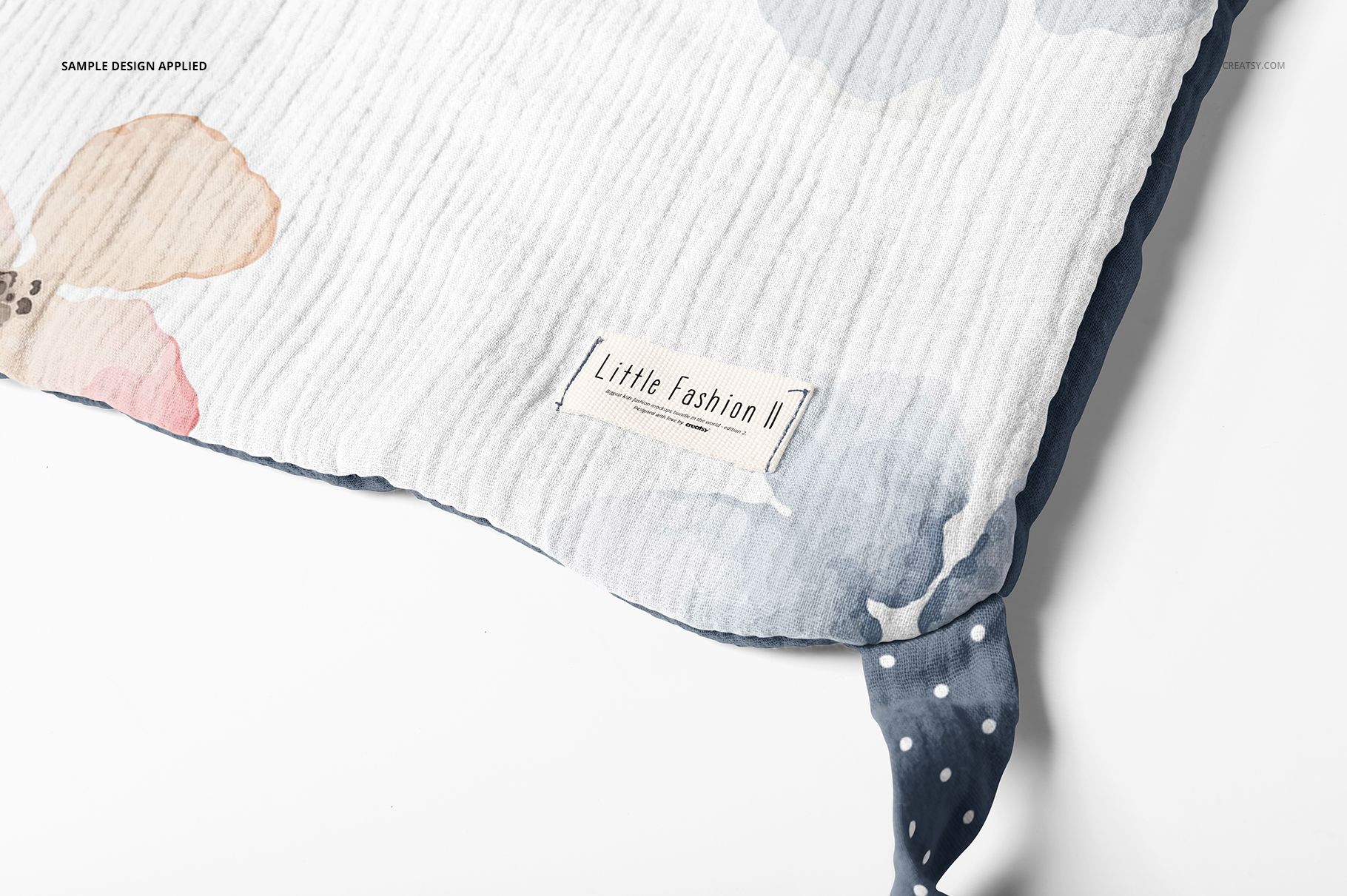 Detailed view of a swaddle wrap mockup featuring pastel flower prints, stitched label, and polka dot corner accent.
