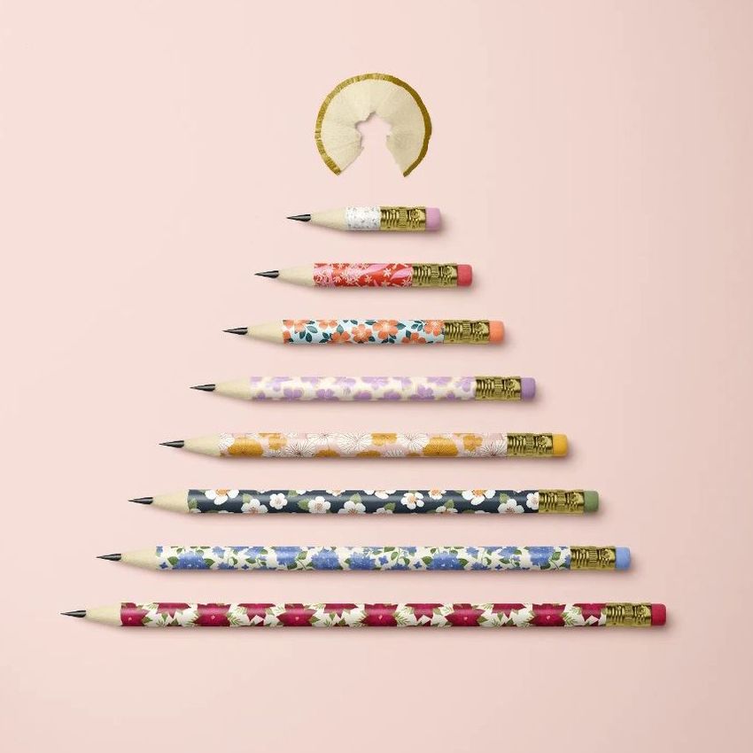 Pencil Christmas tree mockup showing seven patterned pencils arranged in a tree shape on a pale pink background with a pencil shaving as the tree topper.
