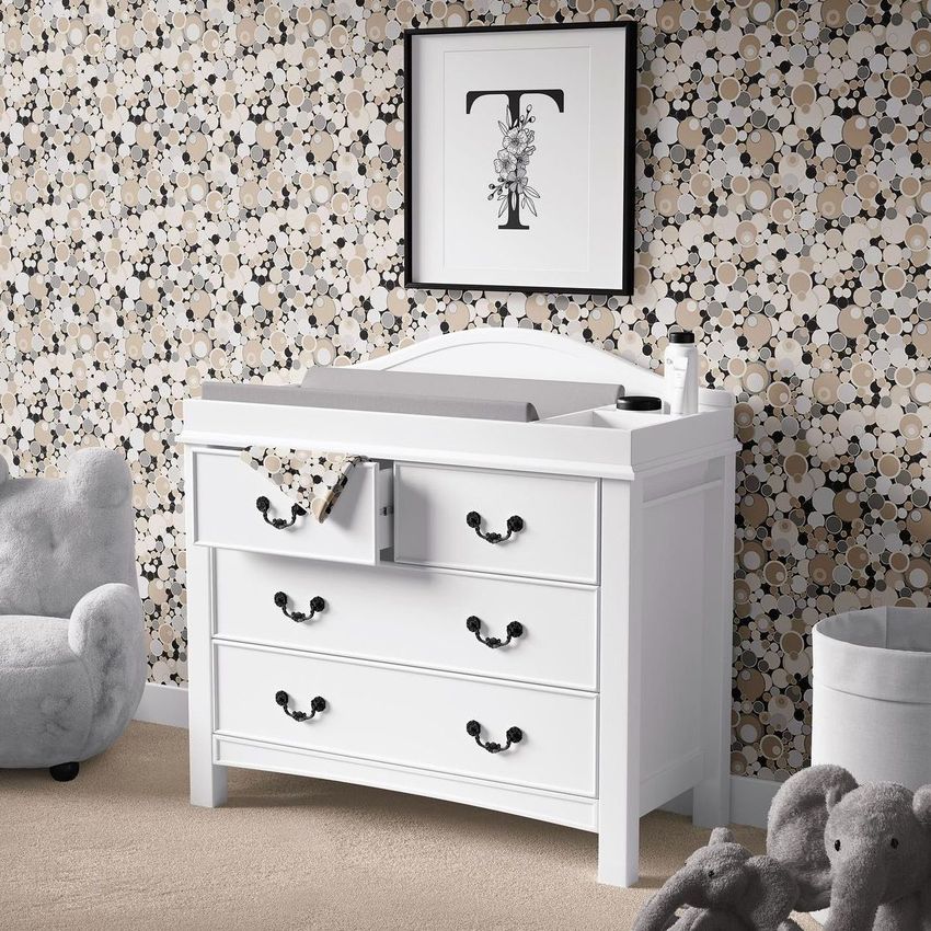Baby room changing pad mockup showing a white dresser with a gray changing pad, plush toys, and patterned wallpaper.