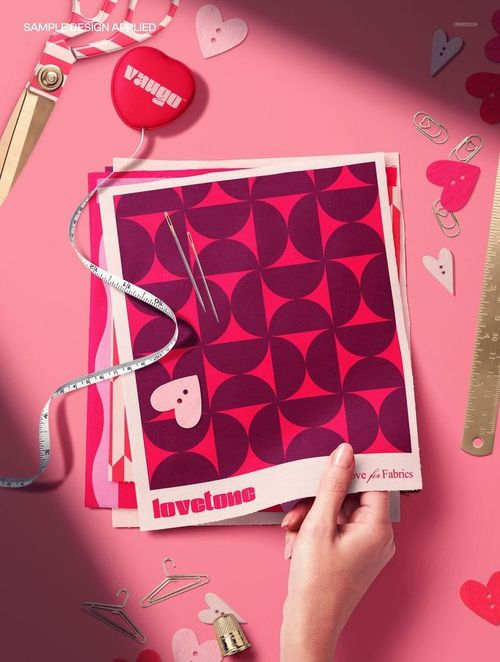 PSD mockup featuring layered fabric swatches in red and magenta, with needles, thread, and Valentine-themed props on a pink background.