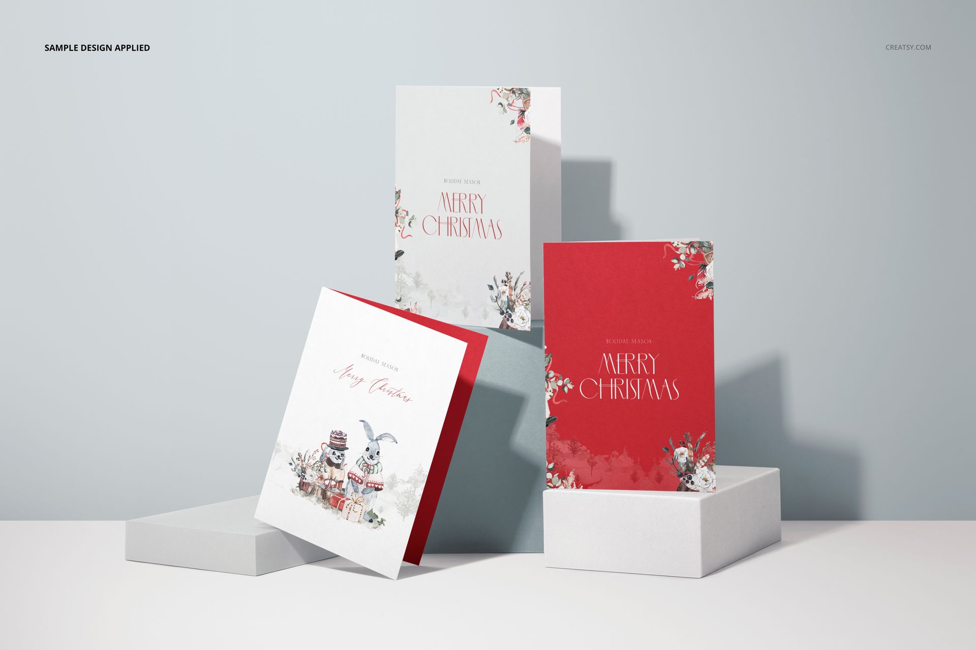 Christmas greeting cards mockup with two vertical and one horizontal card, each with holiday patterns and a neutral backdrop.