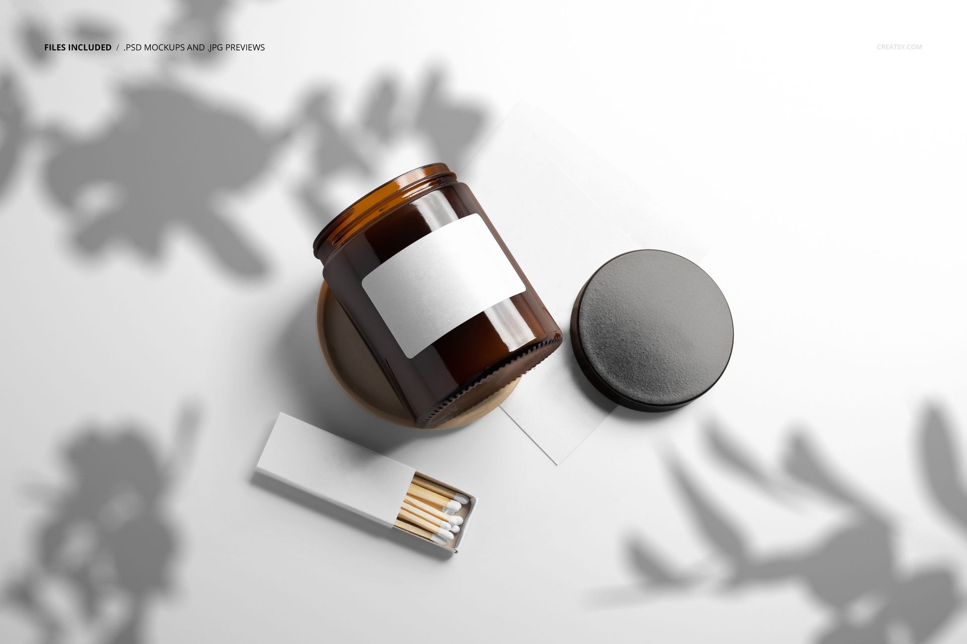 PSD mockup of an amber jar candle with a plain label, black lid, and matches arranged on a light background.