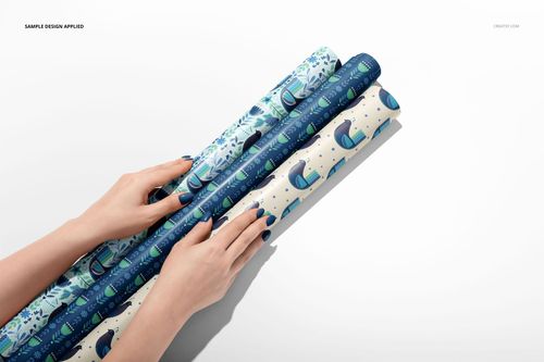Rolled gift wrapping paper mockup with various blue and teal patterns, held by hands against a white backdrop.