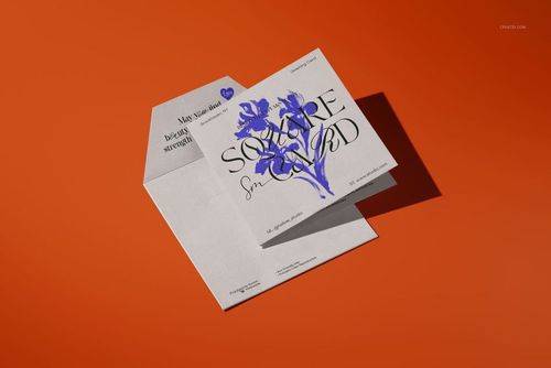 Square greeting card mockup displayed with matching envelope on an orange background, featuring blue floral artwork.