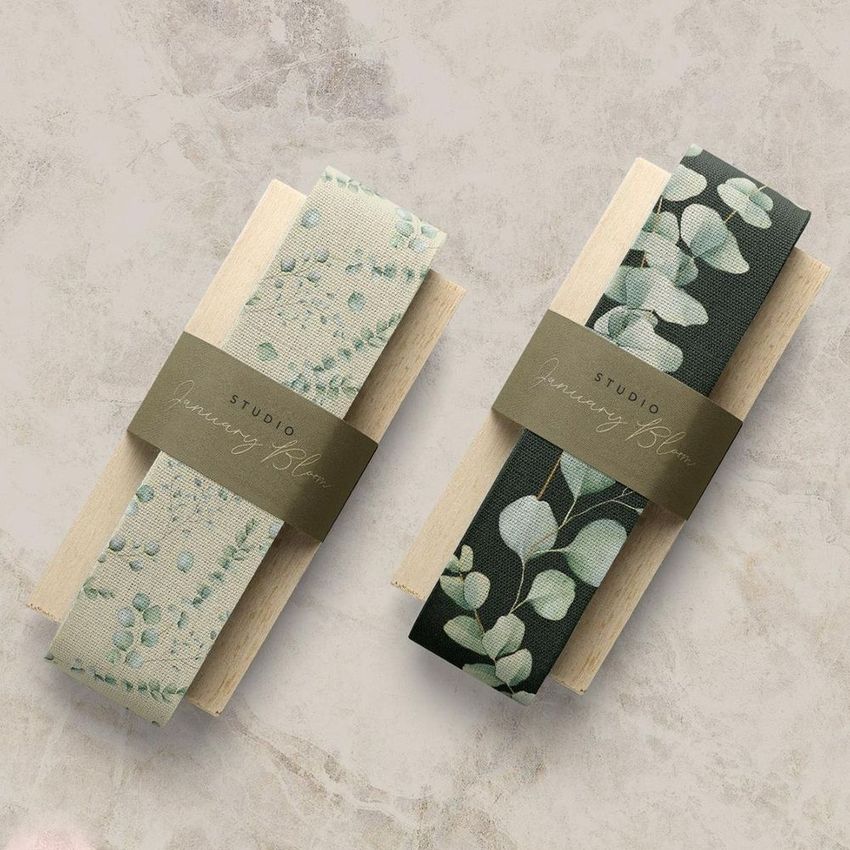 Two cotton ribbons mockup displayed on wooden paddles, featuring botanical patterns in soft green and dark green tones.