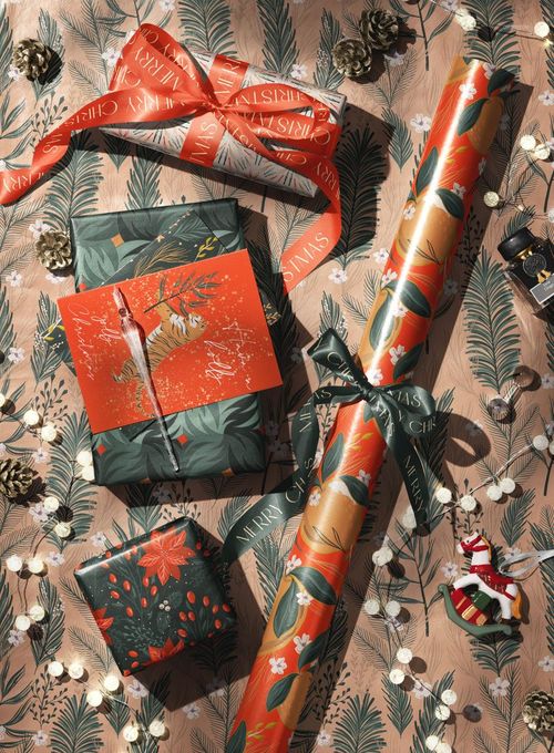 Christmas wrapped gift boxes with festive ribbons and patterned wrapping paper, viewed from above on a decorated surface.