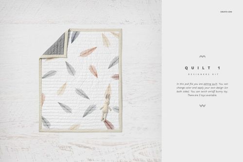 Crib bedding mockup showing a quilt with multicolored feather design and a small plush bunny on a light background.