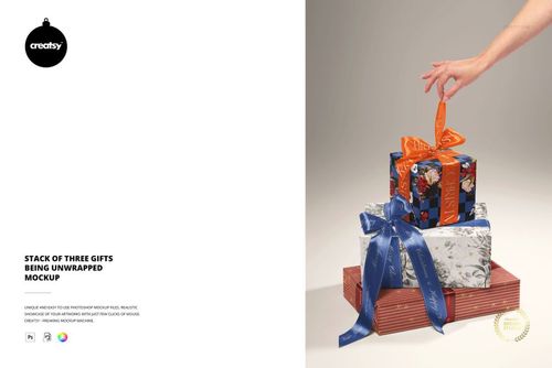 Hand unwrapping ribbon from a pile of three Christmas presents with decorative wrapping paper and bows, mockup scene.