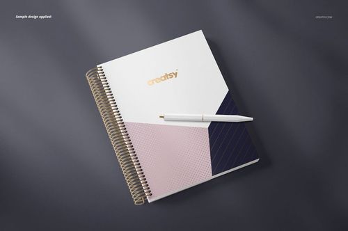 Spiral-bound planner mockup featuring a modern geometric cover in white, blush pink, and dark blue, viewed from above.