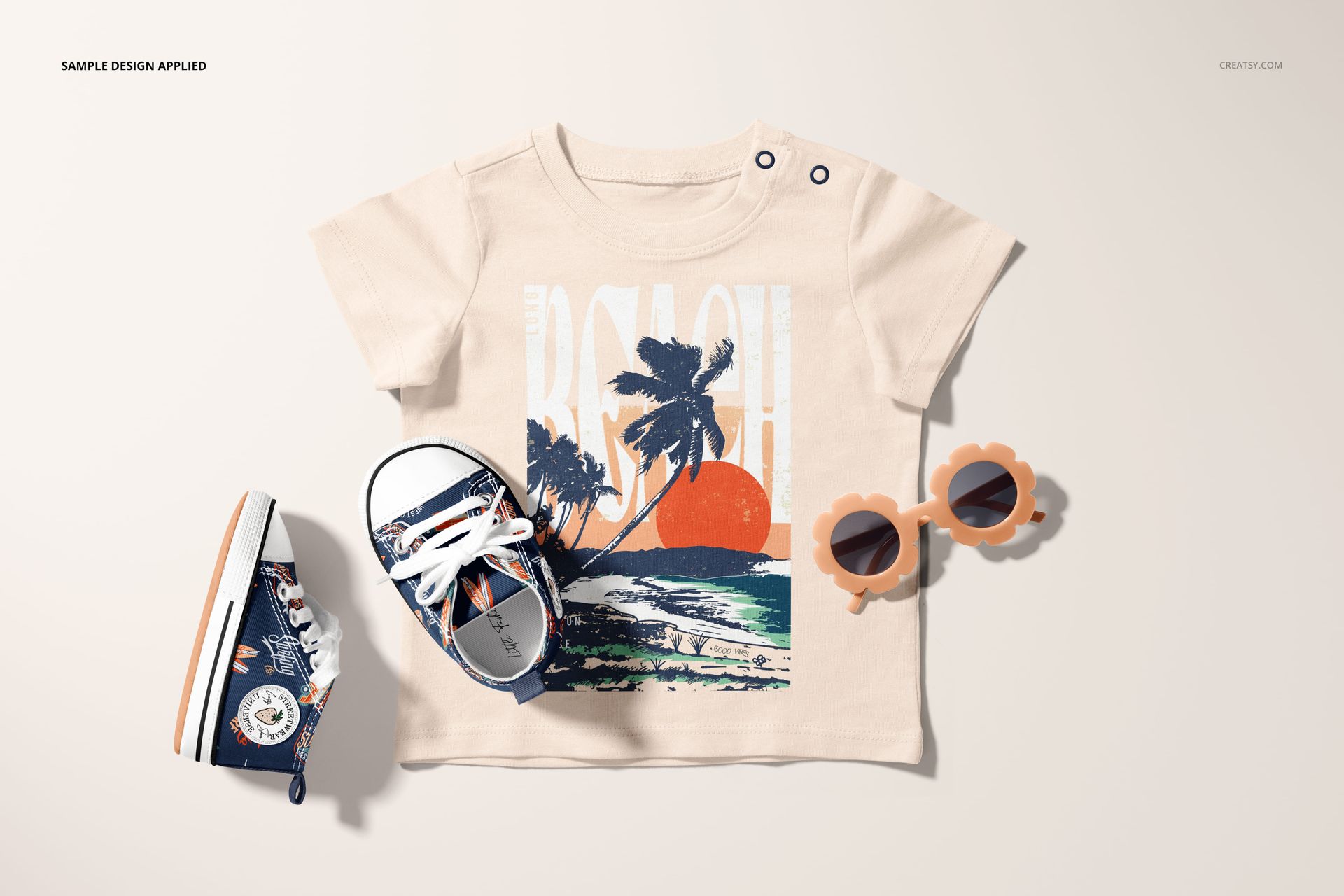 Infant t-shirt mockup with a beach and palm tree print, displayed flat with matching shoes and flower-shaped sunglasses.