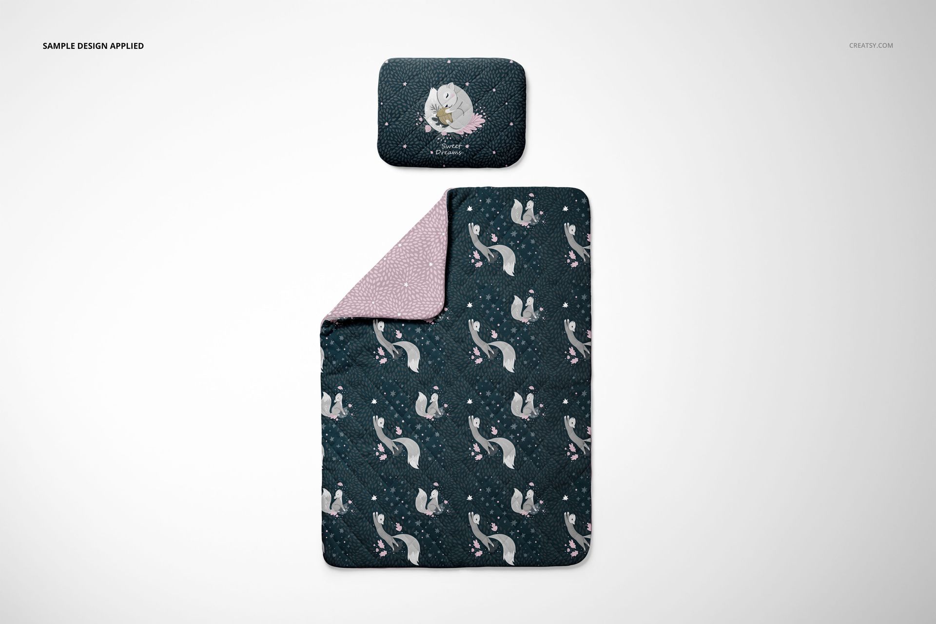 Top view of a baby bedding set mockup showing a pillow and quilt with dark blue swan design and pink inner lining.