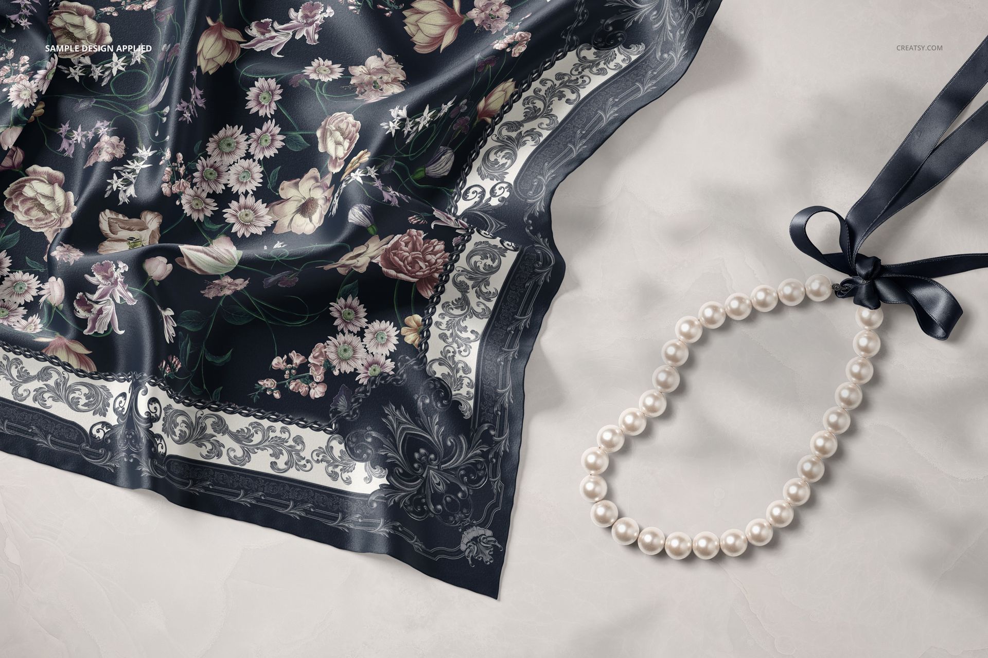 Silk scarf mockup featuring intricate floral designs and decorative border, shown from above on a pale background.