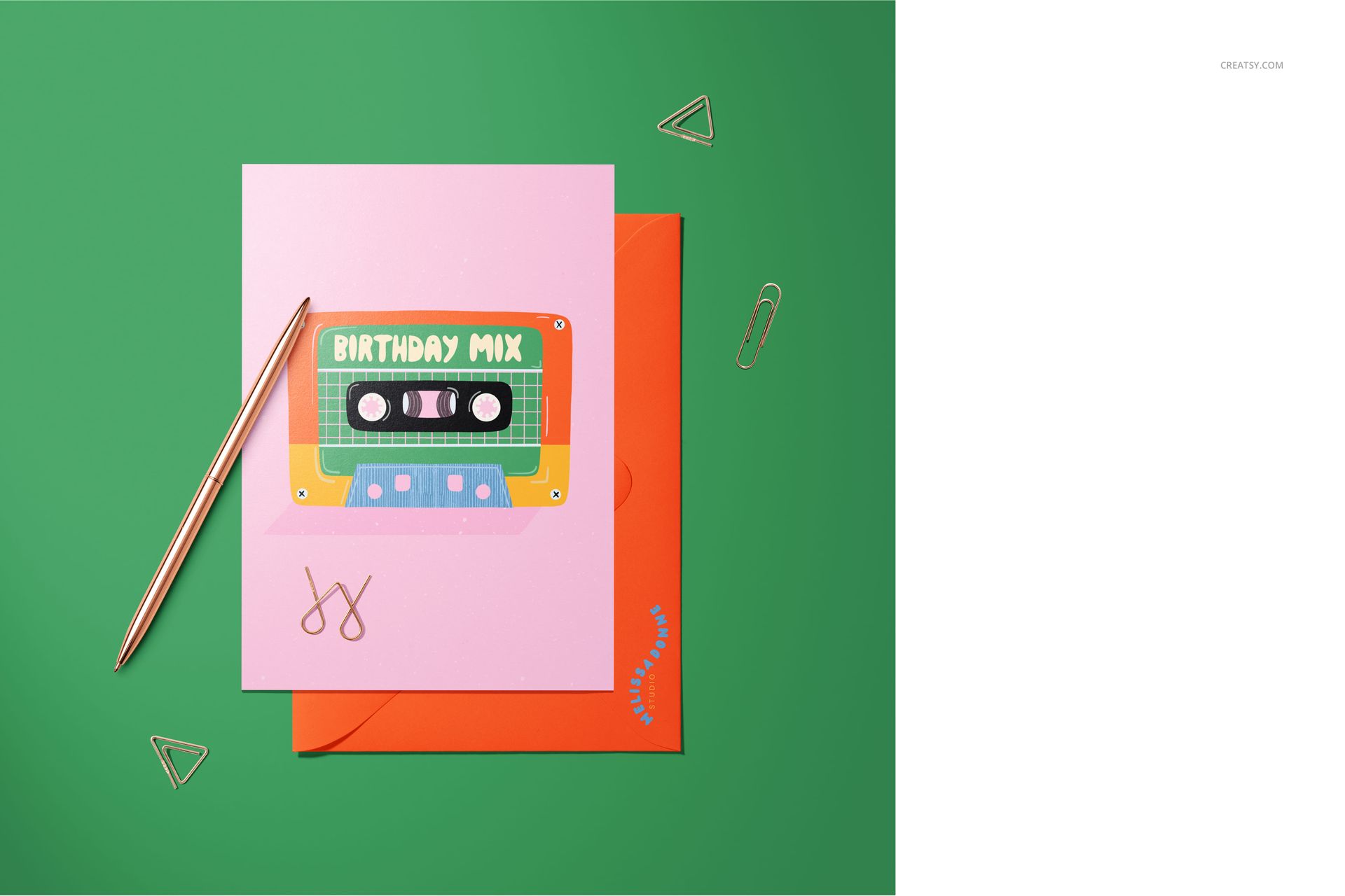 A5 card mockup featuring a pink greeting card with a colorful cassette design, placed on an orange envelope on a green desk.