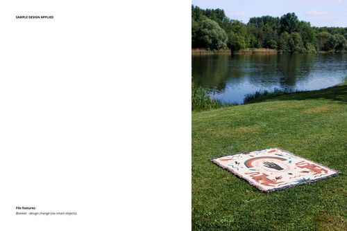 Patterned throw blanket mockup displayed outdoors on grassy ground near water, surrounded by trees and blue sky.