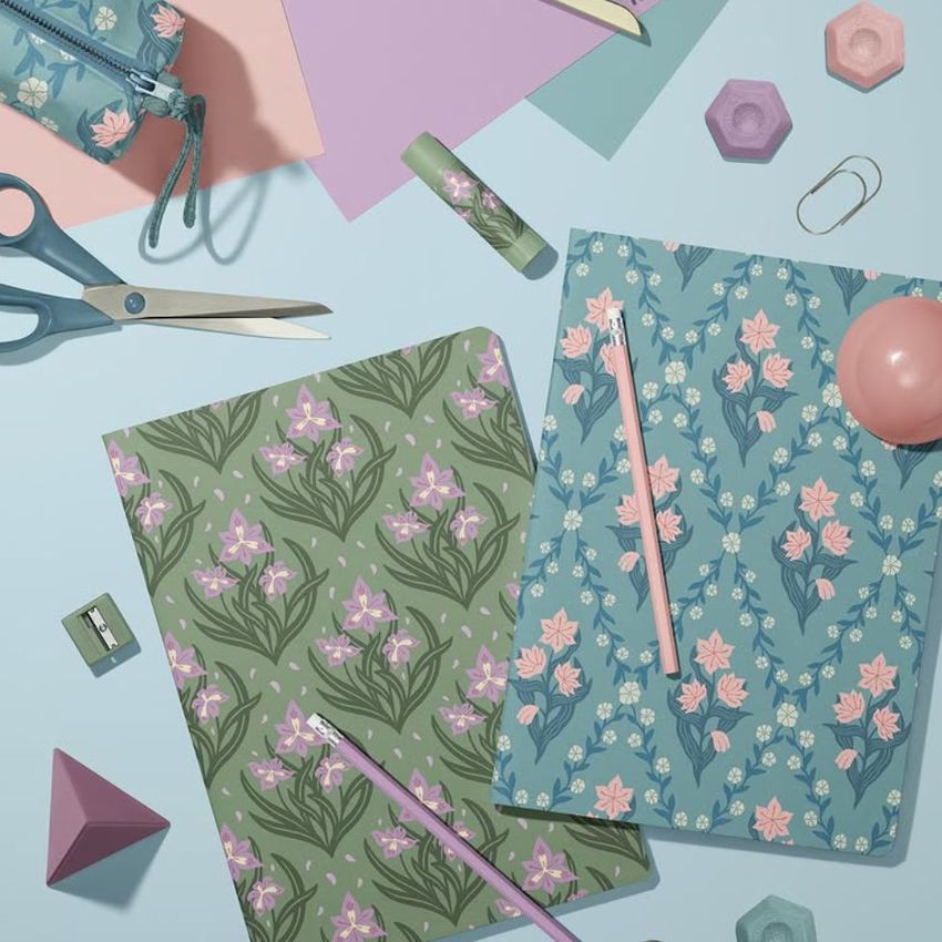 Stationery mockup featuring two A4 notebooks with vintage floral patterns, surrounded by pastel office supplies on a light blue surface.