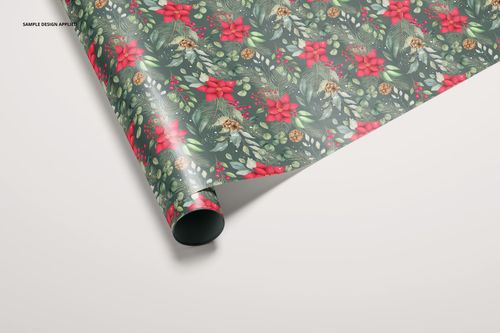 Front angled view of a mockup gift wrapping paper roll showing a holiday-themed design with red and green botanical elements.
