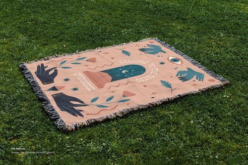 Fringed jacquard blanket mockup displayed outdoors on a grassy surface, showing a whimsical design in muted tones.
