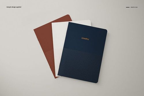 A5 notebook PSD mockup showing three closed notebooks with solid color covers and subtle dotted designs in a top view.