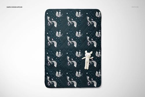 Double-sided baby bedding set mockup showing a quilt with whimsical fox design and a small plush toy from above.