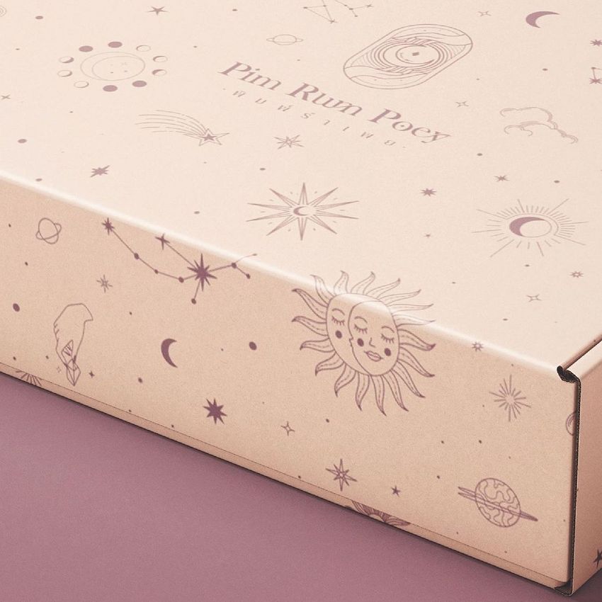 Mailing box mockup featuring celestial illustrations like the sun, stars, and planets on a light beige background, shown at an angle.