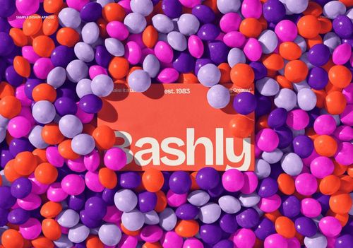 Business card mockup placed in a colorful ball pit with orange, purple, and lavender spheres, viewed from above.