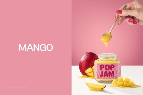 Front view of a mango jam jar mockup with a pink label, surrounded by mango slices and a whole mango on a white surface.