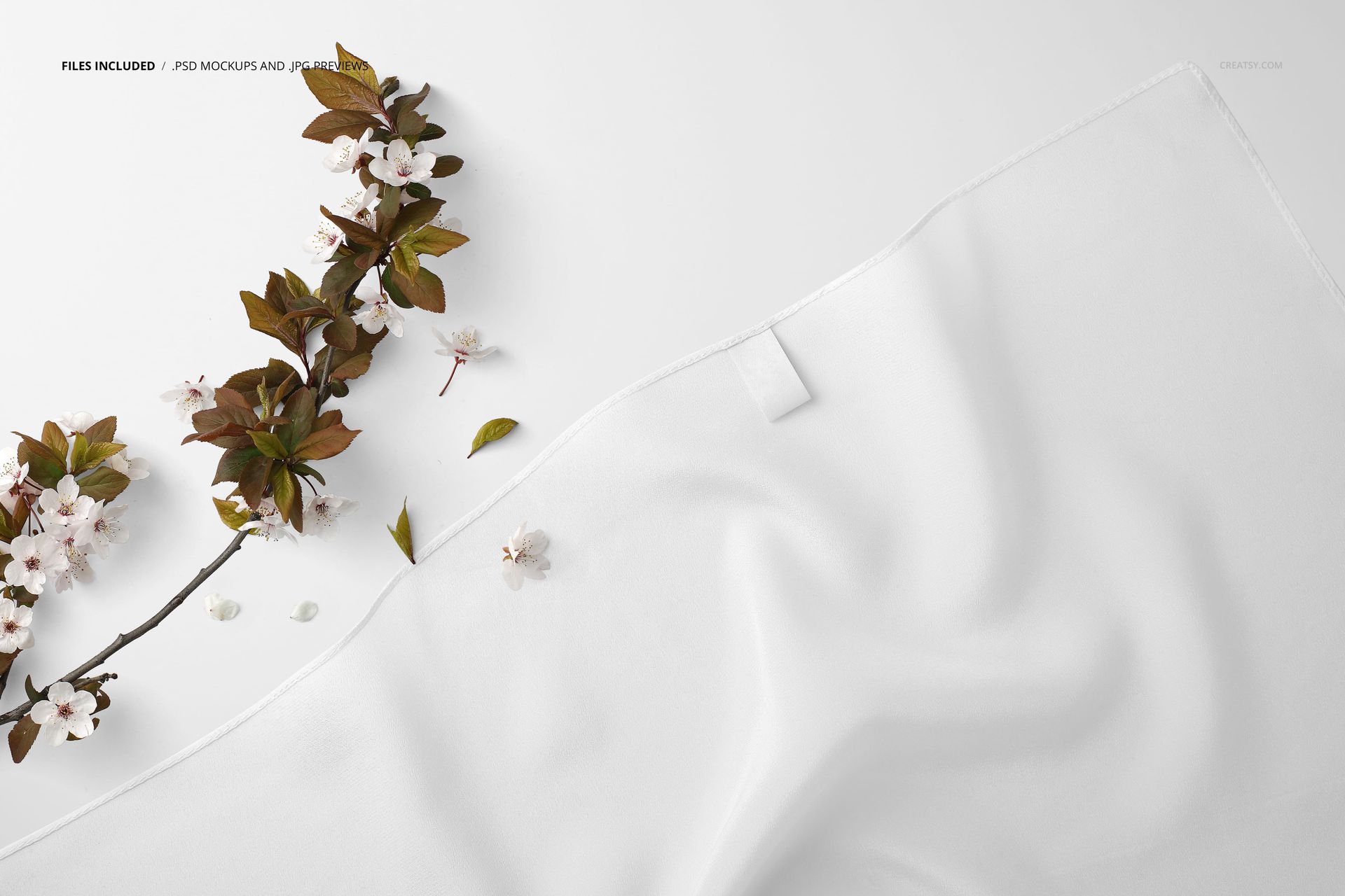White silk scarf mockup featuring machine hemmed edges, shown in close-up with delicate flower branches nearby.