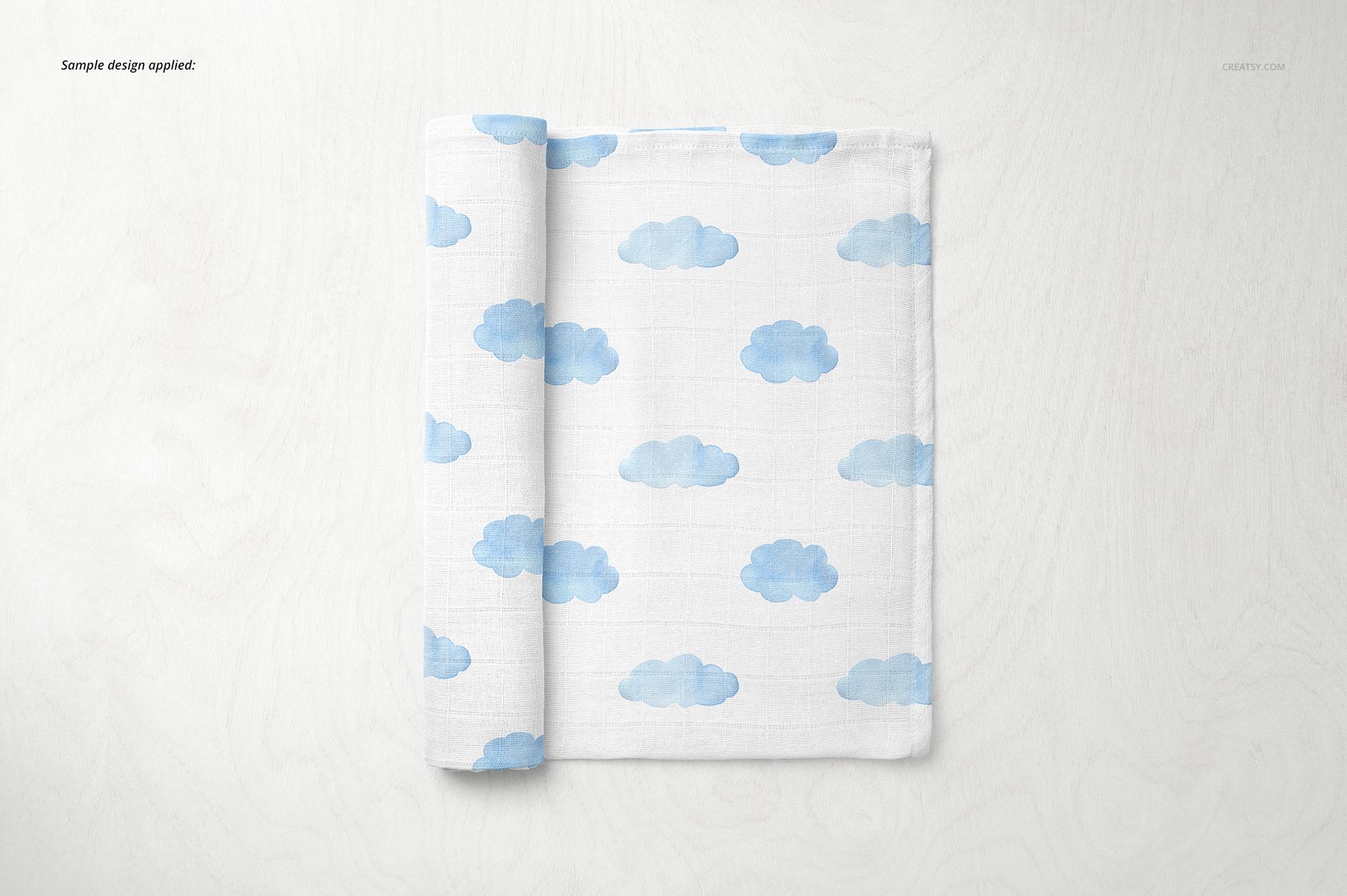 Baby muslin square nappy mockup featuring soft blue clouds printed on white fabric, displayed from above.