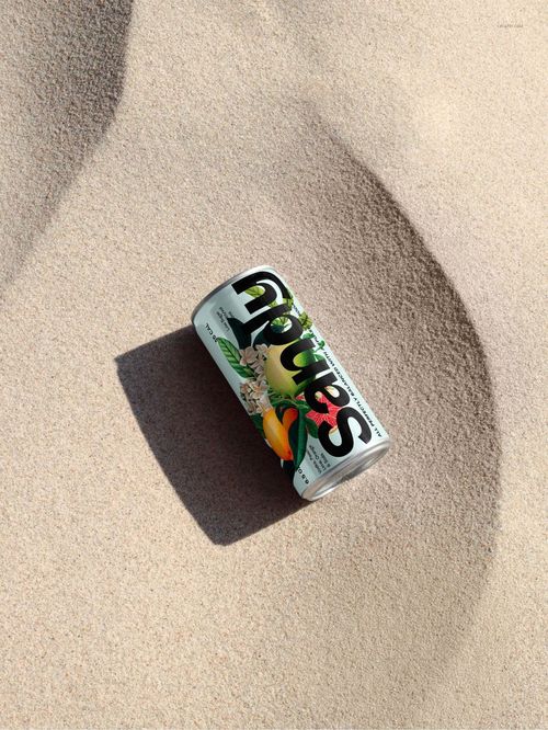 200ml can with colorful label lying on light sandy beach, viewed from above with natural sunlight and shadows.