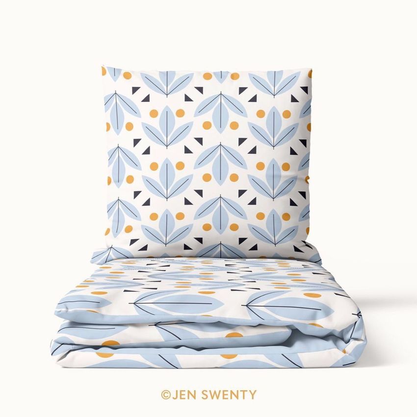 Bedding set mockup featuring a pillow and folded duvet with a geometric petal pattern in blue, yellow, and black on white.