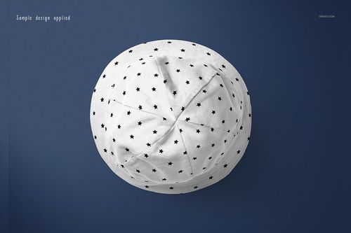 Top view of a baby hat mockup with a white fabric featuring a small black star pattern, set against a dark blue background.