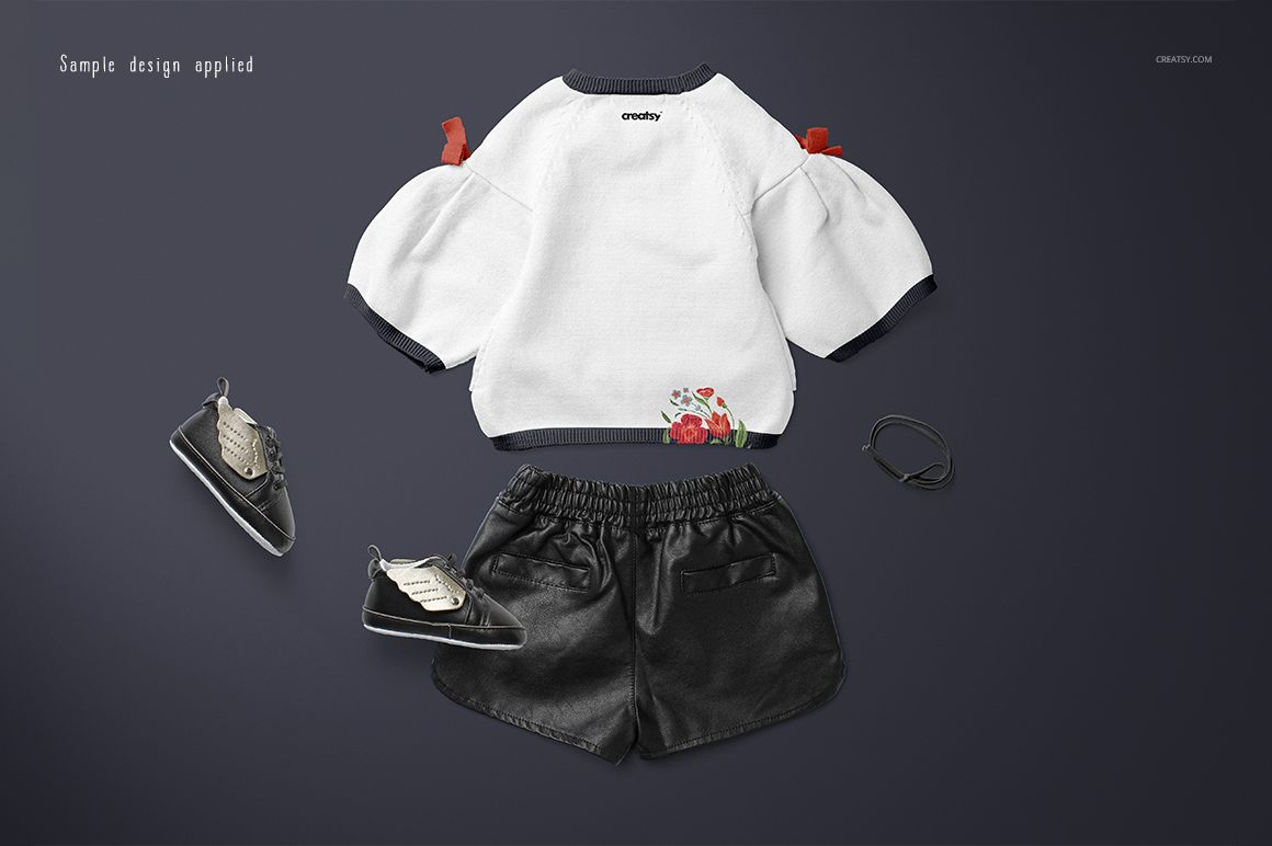 Kids sweater mockup set featuring a white long-sleeve top with floral accents, black shorts, shoes, and a bracelet on a dark background.