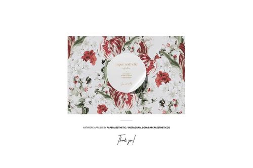 Top view of a fabric mockup displaying a detailed floral print with sewing accessories arranged on the surface.