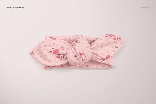 Top view of a soft pink baby headband mockup featuring a knotted center and scattered floral and geometric motifs.