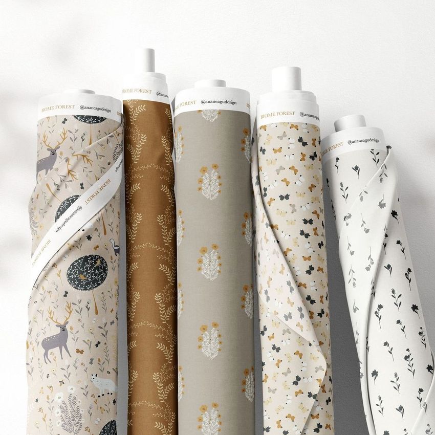 Fabric rolls mockup showing five upright rolls with botanical and animal patterns in earthy tones, set against a light background.