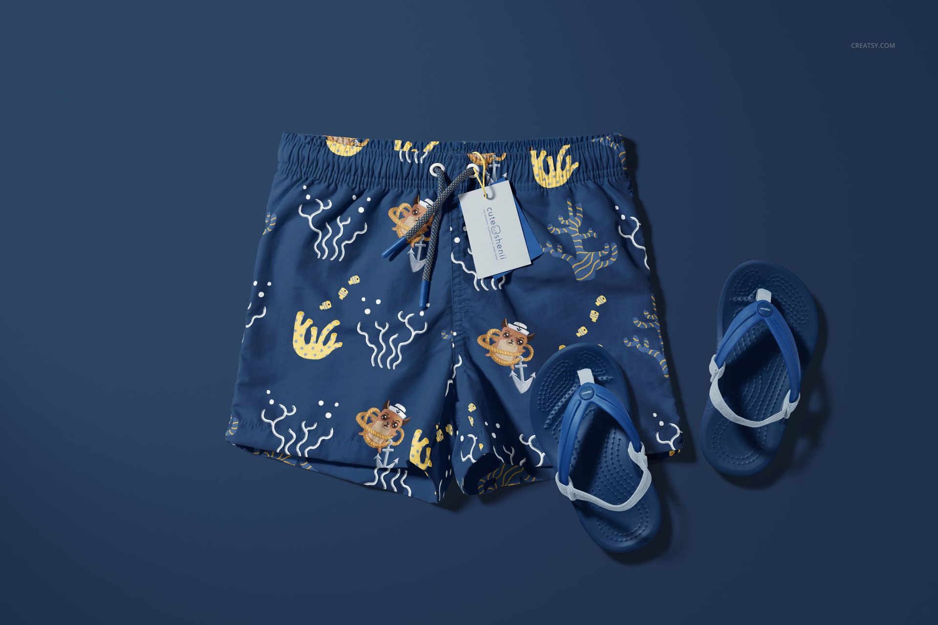 Kids swim shorts mockup featuring a marine-themed print in blue tones, displayed with matching blue flip-flops on a blue surface.