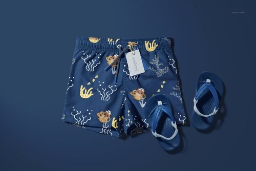 Kids swim shorts mockup featuring a marine-themed print in blue tones, displayed with matching blue flip-flops on a blue surface.